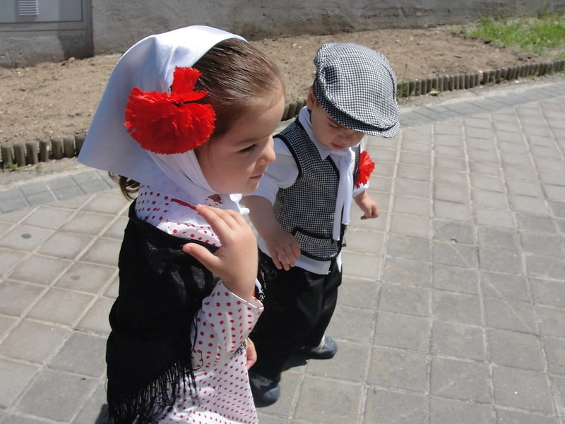 Los trajes de chulapo son la vestimenta típica durante las fiestas de San Isidro 2026. Chaleco, gorra y clavel para los chicos, y pañuelo, lunares, mantilla y clavel para las chicas.