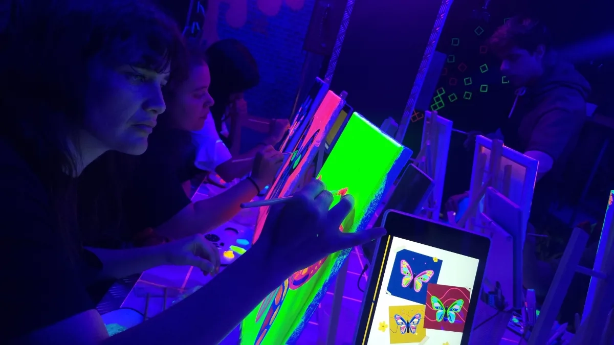 Grupo pintando sus cuadros con luz neón en Tinto y Tinta Madrid