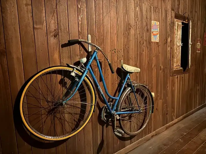 Bicicleta antigua apoyada en una pared de madera en la sala de escape room KM 18 de Alicante